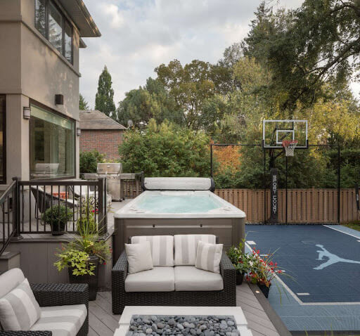 A covered raised deck with a spa in a backyard.