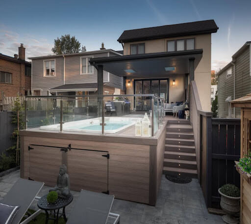 A covered deck with a spa and stairs.