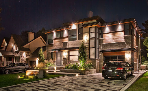 Landscaped driveway and front yard of a house with outdoor lighting.