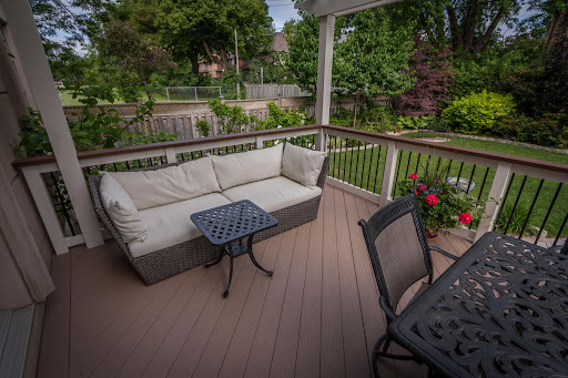 A seating area on a deck with a flower planter.