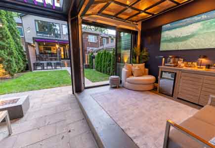 Urban backyard with Fiberon deck, louvered pergolas, 3-season room, and outdoor dining — custom Toronto staycation space.