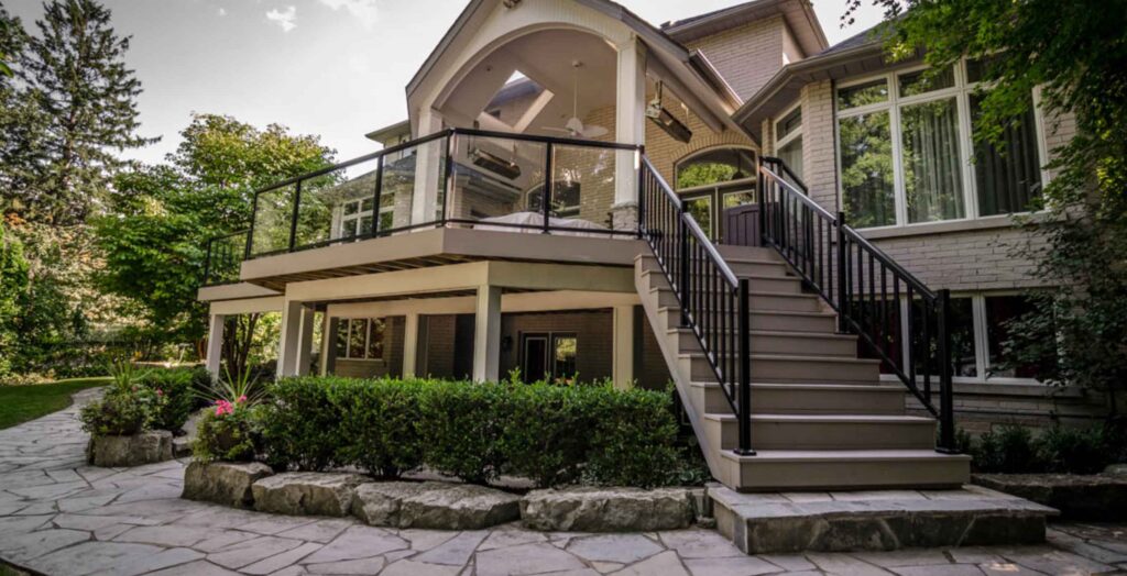 Second-floor covered deck with a protected stone patio underneath for expanded outdoor living space