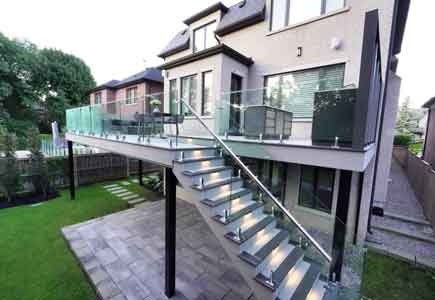 Two-level Wolf PVC deck with outdoor kitchen, firetable lounge, frameless glass railings, and long-span beam in Toronto backyard