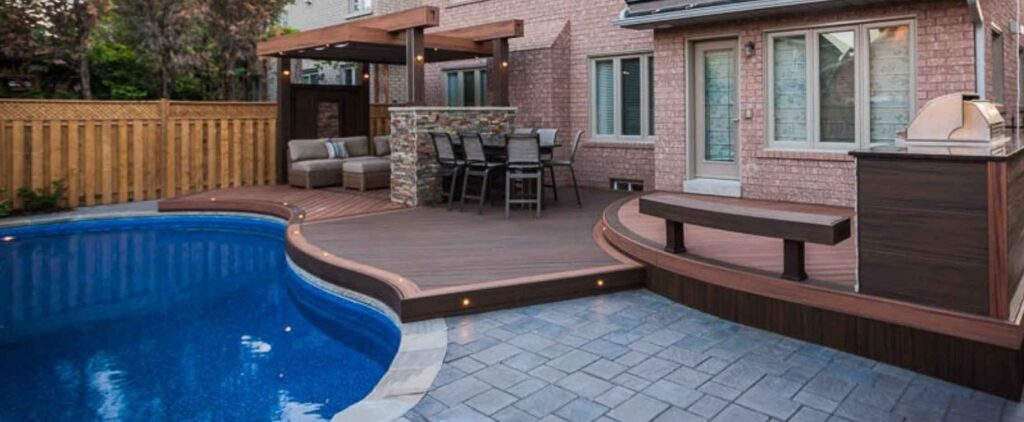 Curved deck with multi-level stone work beside a pool, creating a seamless transition between spaces