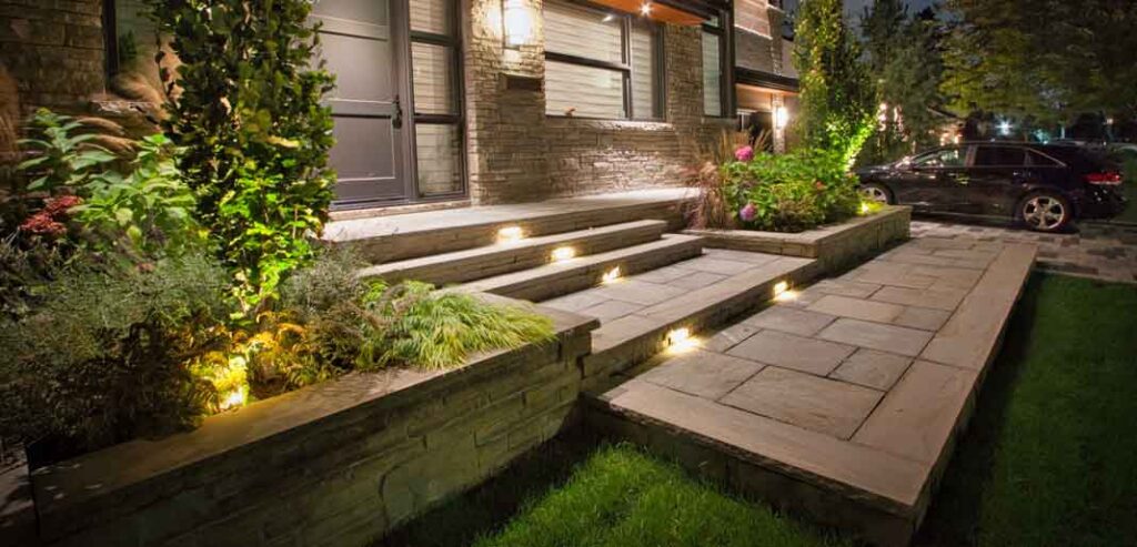 Outdoor lighting highlighting the house, landscaping, and stonework for safety and nighttime ambiance