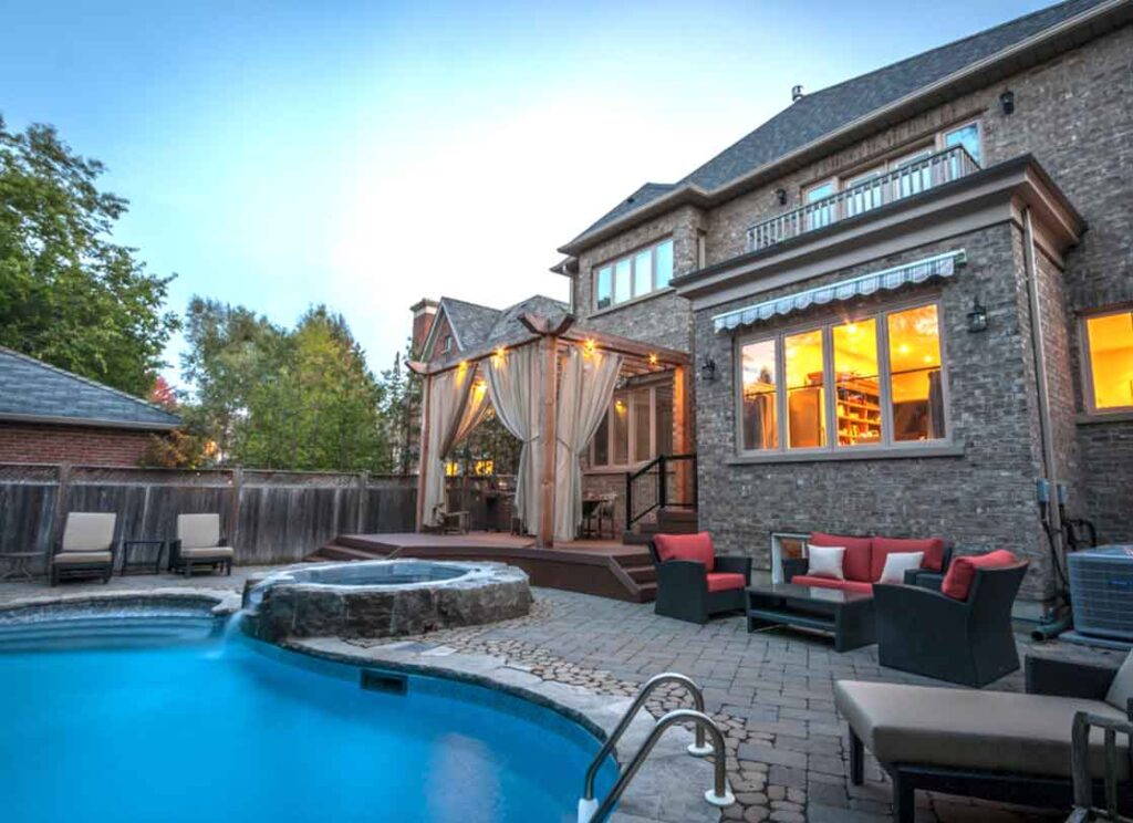 Luxury backyard with pool, hot tub, dining deck, and stonework creating a seamless outdoor living space