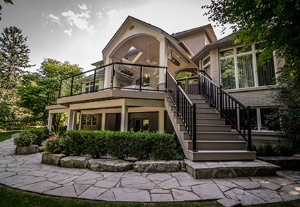 Elevated Mississauga deck with a large roof, skylights, heaters, outdoor kitchen, wood-finished pillars, and spacious stone patio underneath.