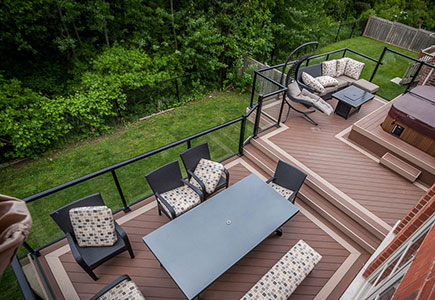 Two-level Richmond Hill deck with hot tub on upper level, contrasting composite colours, glass railings, and scenic ravine views.