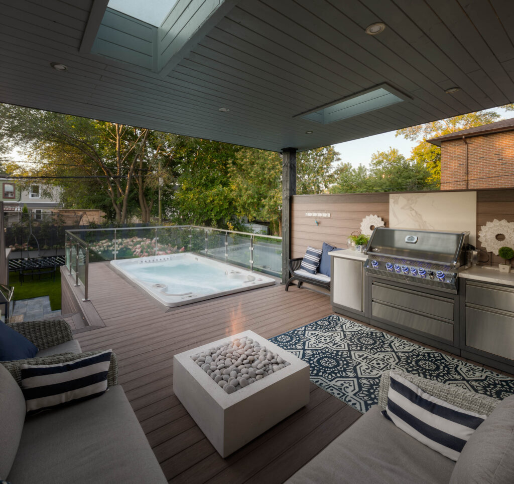 Pavilion in East York built over a deck, overlooking a deep backyard with a swim spa, outdoor kitchen, fireplace, and comfortable seating, creating the perfect place to relax and unwind.