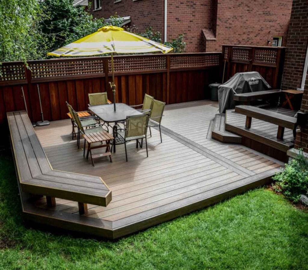 Two-level composite Trex deck in Ancaster with an upper level off the main floor and a lower seating area with BBQ, featuring built-in benches throughout for comfortable outdoor living.