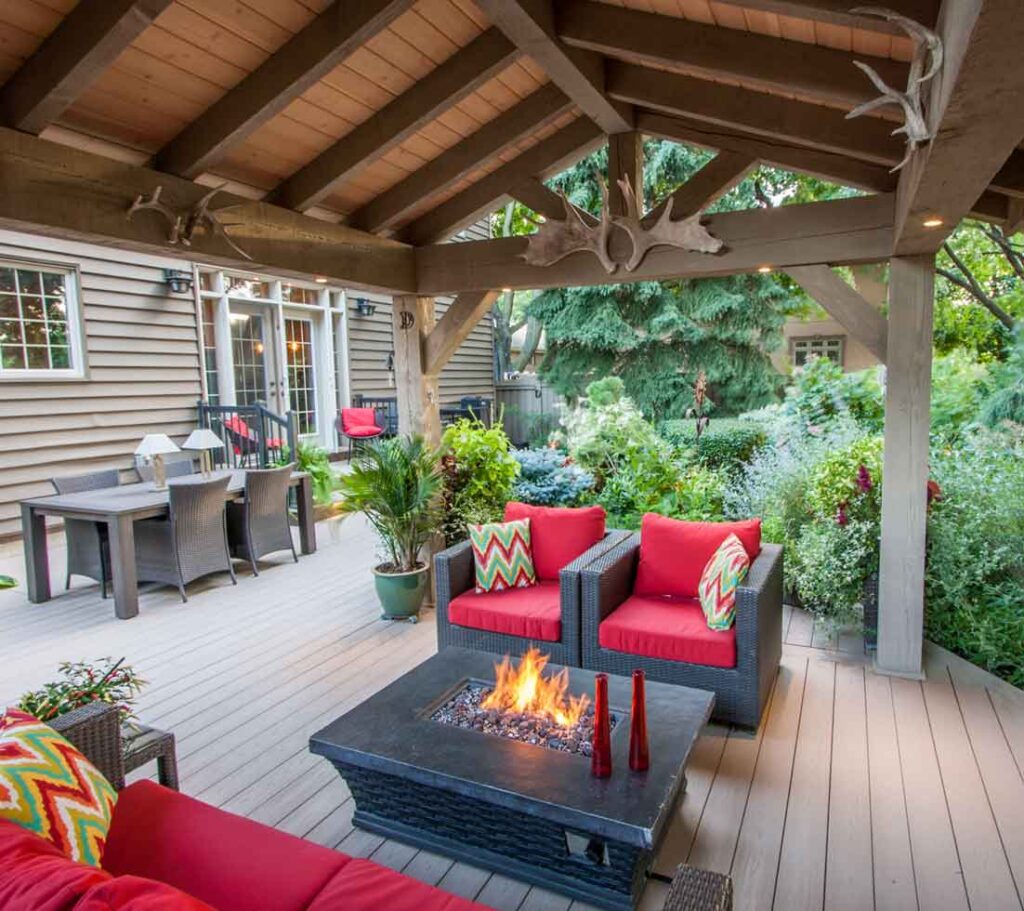 Modern PVC deck with a timber roof, outdoor fireplace, and lush greenery creating a luxury staycation backyard