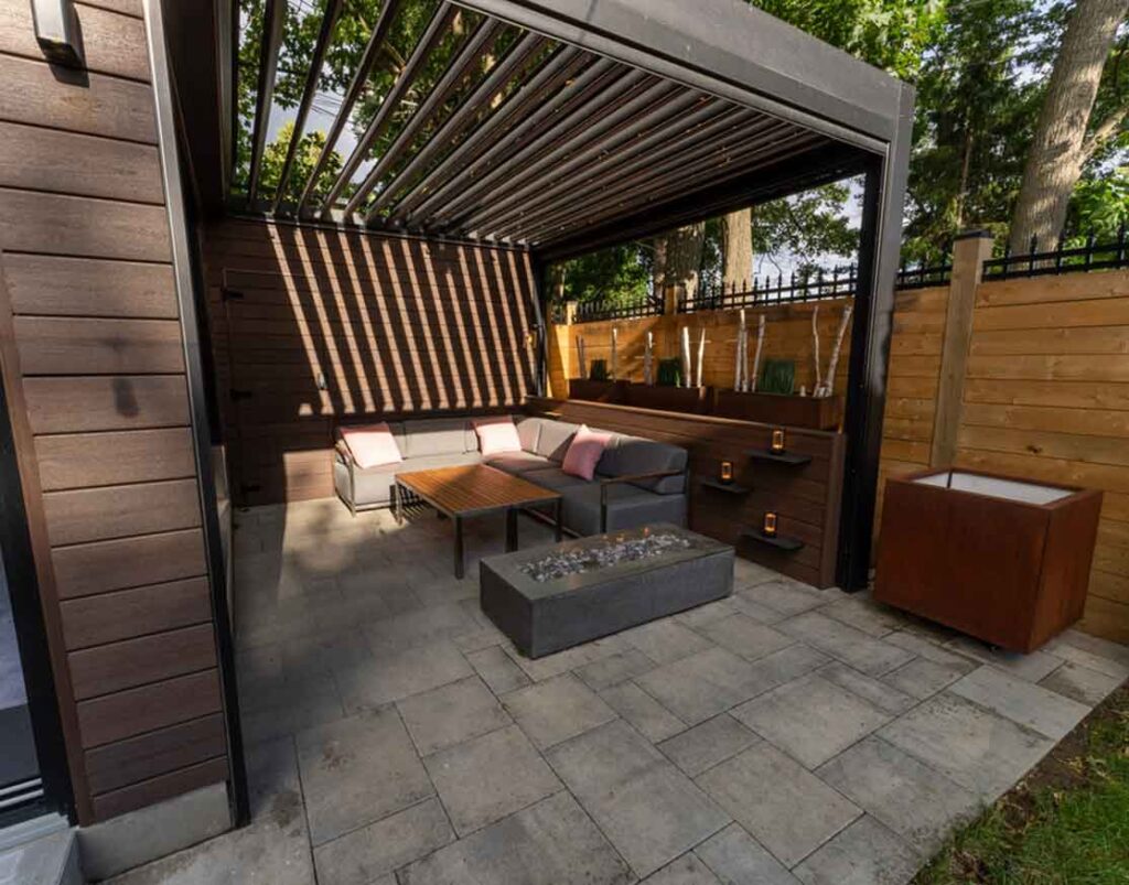 Louvered pergola connected to a three-season room, featuring adjustable roof panels and built-in lighting for flexible outdoor living and evening enjoyment