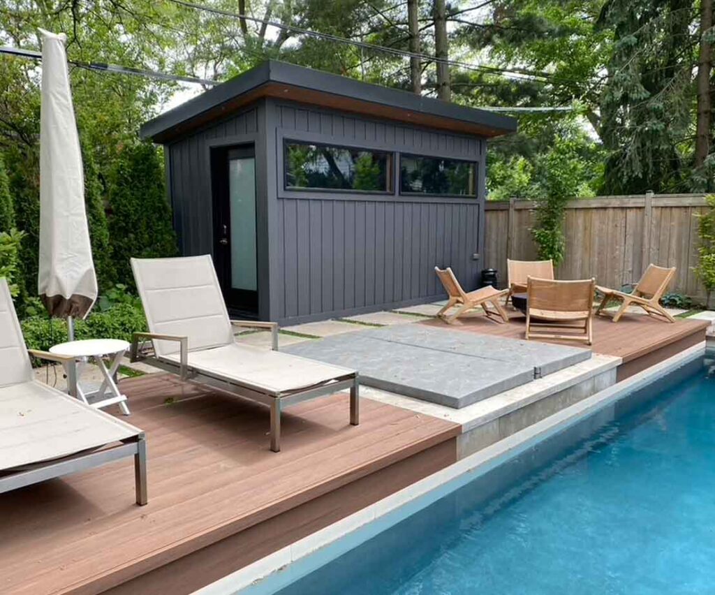 Modern poolside deck built as an extension of stone patio, featuring a seating area and hot tub beside the pool