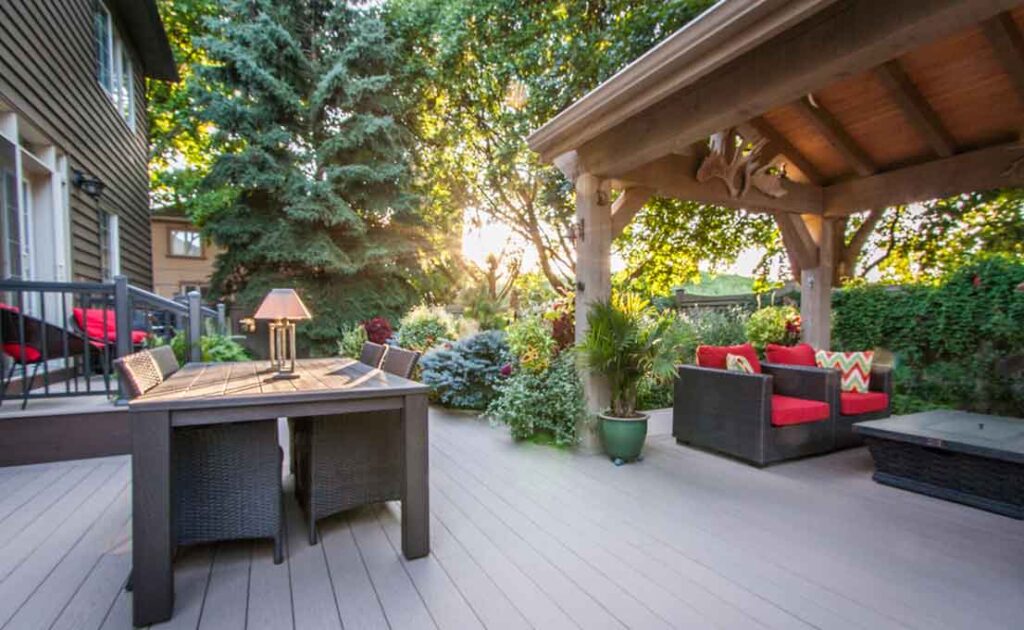 TimberTech Azek PVC deck with an outdoor dining area in the foreground and a timber pavilion surrounded by lush gardens