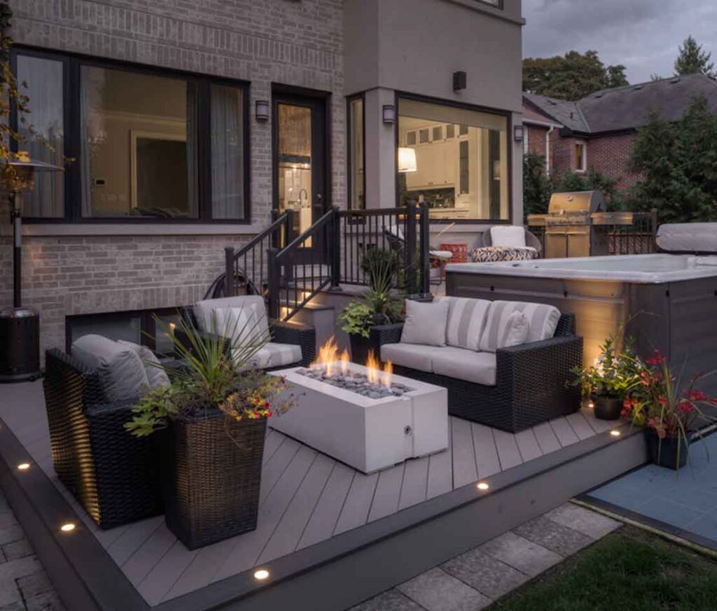 Two-level PVC deck in Oakville with a fireplace and lounge seating on the lower level and a swim spa on the upper deck flush with the hom