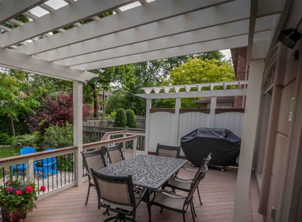 Traditional white painted cedar pergola in a Toronto backyard, adding partial shade and enhancing the classic look of the home