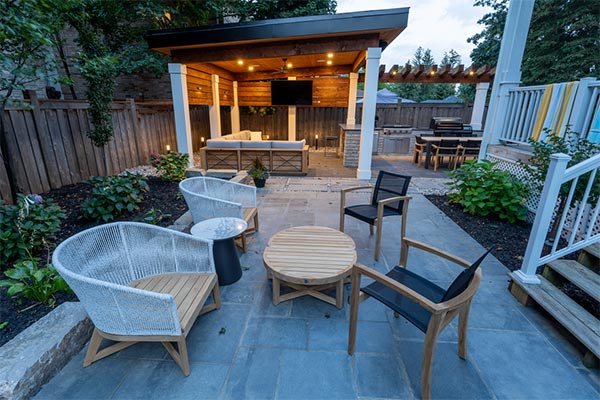 Toronto backyard side yard featuring custom cabana with lounge and TV, adjacent coffee seating area, and large outdoor kitchen with dining space for 10.