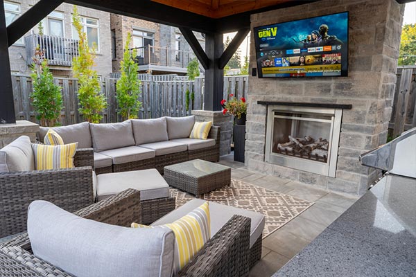 Toronto backyard featuring a large custom pavilion with fireplace feature wall and TV above, covered seating area, and fully equipped outdoor kitchen.