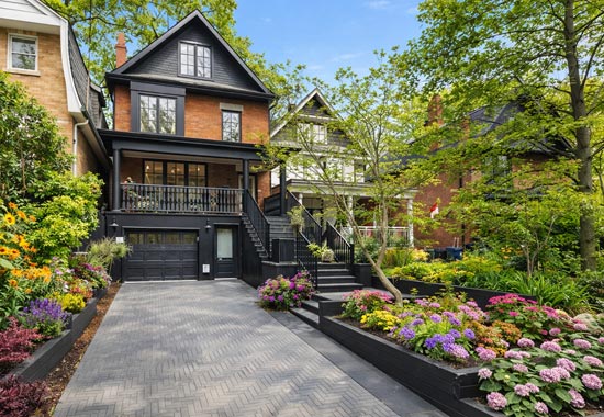 Custom driveway in The Beaches Toronto featuring narrow layout, natural stone front steps, and covered porch above garage