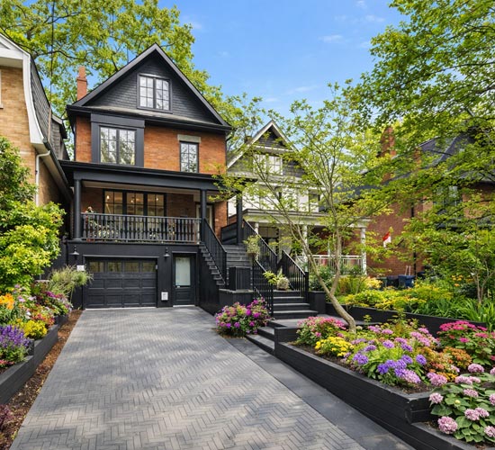 Front yard landscaping in Beeches featuring planting beds, driveway with garage access, and natural stone stairs to porch.