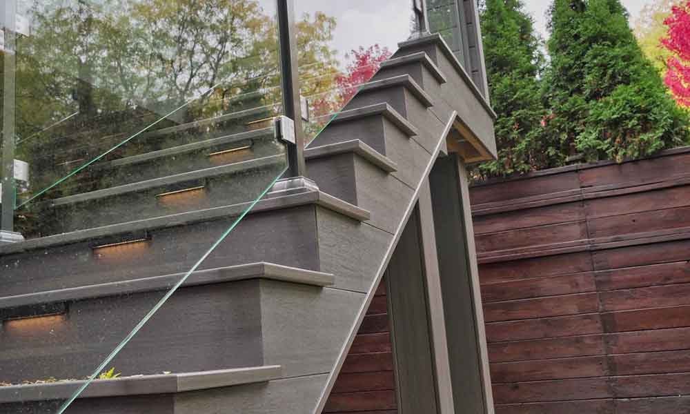 Composite deck stairs with built-in lighting and glass railing creating a clean, modern look