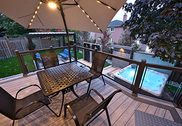 Large PVC deck with upper dining level and lower level featuring hot tub, louvered pergola, seating, and integrated lighting