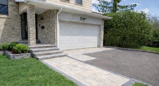 Asphalt driveway upgrade featuring interlock paver extension seamlessly integrated with natural stone front porch