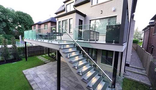 Large second floor deck with steel framing to maximize spans, PVC decking, glass railings, and open space below for landscaping