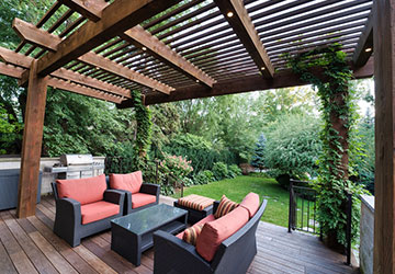 Wood deck with pergola, outdoor kitchen, and adjacent lounging area designed for entertaining