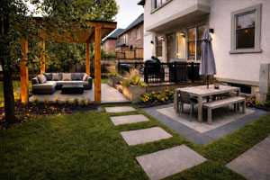 Luxury Toronto backyard with modern cedar cabana, outdoor sofa lounge, raised deck with BBQ, and stone patio dining area