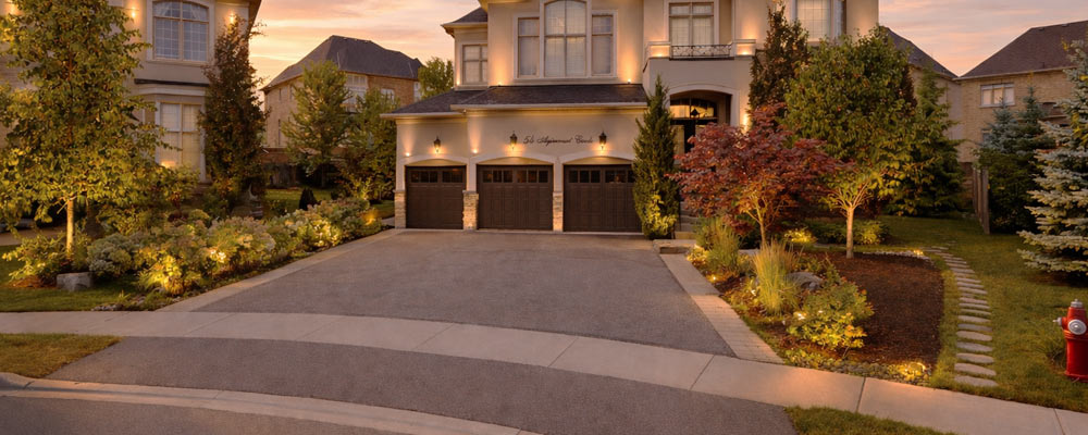 Driveway extension in Brampton with asphalt driveway widened using paver border and landscaped garden beds on both sides.
