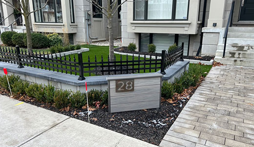 Front yard landscaping featuring a stone feature wall with integrated house number