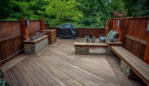 Rooftop deck in Ipe hardwood with built-in planters, benches, privacy screens, lighting, and ravine views