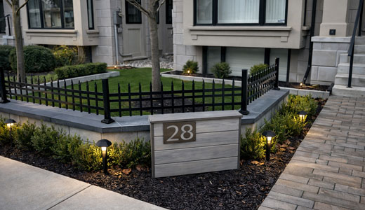 Front yard landscaping featuring a stone feature wall with integrated house number