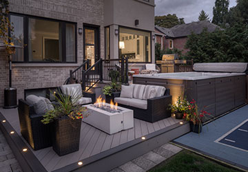 Two-level PVC deck with swim spa, fire table, and warm evening lighting