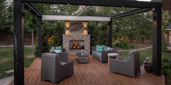 Backyard landscaping integrating custom deck, pergola with retractable awning, and built-in fireplace