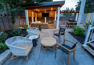 Stone patio with coffee seating area, cabana, and illuminated lounging space in the background