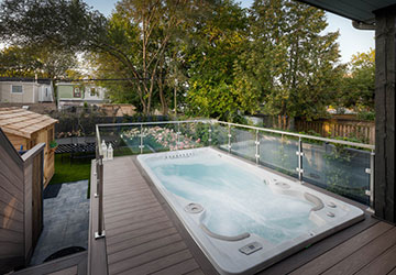 Summer-ready PVC deck with roof cover, swim spa, outdoor kitchen, and comfortable lounging