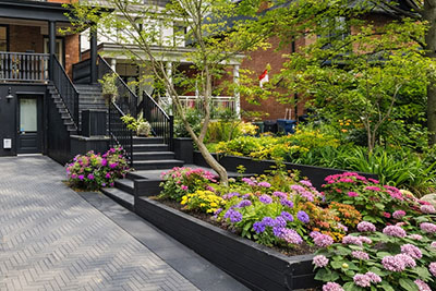 Custom wood retaining wall system for elevated garden beds paired with natural stone steps in a landscaped outdoor space