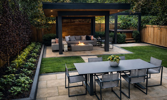 Luxury Rosedale Toronto backyard featuring landscaped greenery, outdoor dining space, modern cabana with fire table seating, and built-in hot tub
