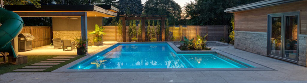 Modern blue pool surrounded by a stone deck finished with porcelain tile pavers