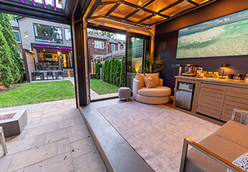 Stone patio with coffee seating area, cabana, and illuminated lounging space in the background