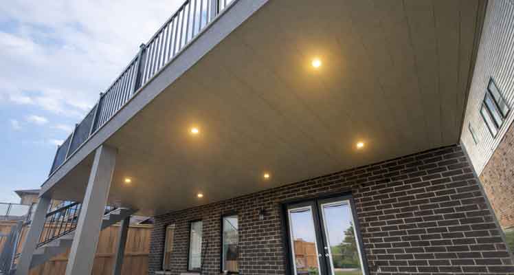 Integrated waterproof deck system that seals the deck above while finishing the ceiling below