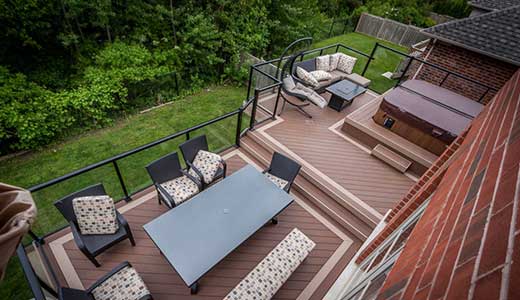 Two-level second floor deck with hot tub overlooking a ravine, featuring glass railings to preserve unobstructed views