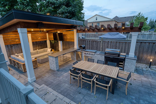 Modern cabana with lounge seating, built-in TV, outdoor kitchen and dining area