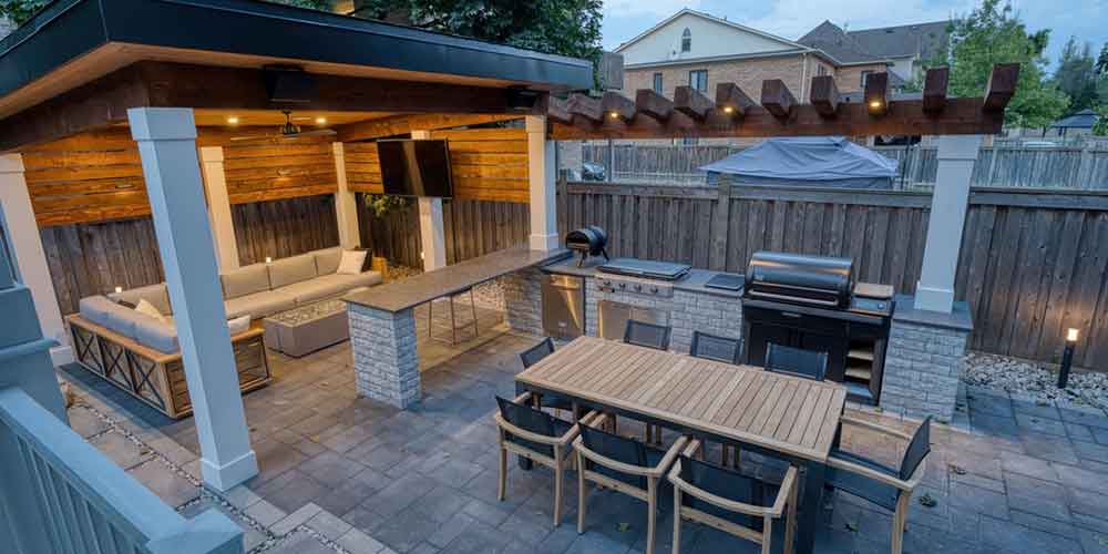 3D backyard landscape rendering showing custom outdoor kitchen, large dining area, cabana lounge and integrated evening lighting design