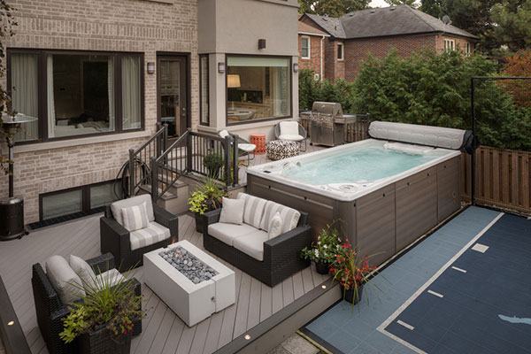 Two level composite deck in Toronto with integrated swim spa and lower lounge area with outdoor fireplace