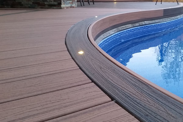 Composite deck boards installed around pool with curved border and low maintenance decking surface