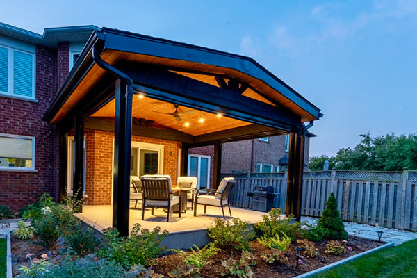 Covered PVC deck with roof structure, exposed timber beams, lighting, seating area and retractable screens