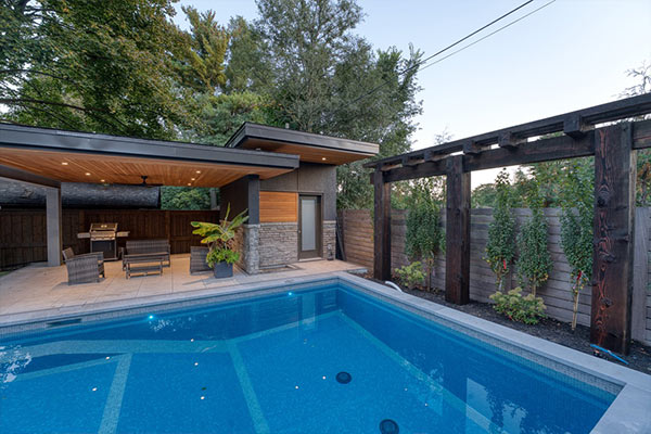 Modern pool cabana with heavy timber structure, changing room and lounge area beside a Caribbean blue swimming pool